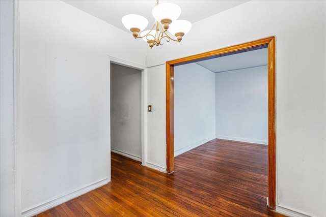 spare room featuring dark hardwood / wood-style flooring and an inviting chandelier