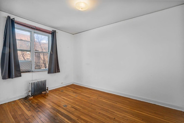 spare room featuring hardwood / wood-style floors and radiator heating unit