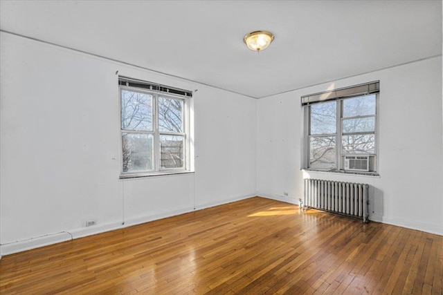 spare room featuring hardwood / wood-style flooring, radiator, and cooling unit