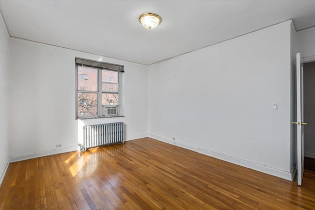 empty room featuring cooling unit, radiator heating unit, and hardwood / wood-style floors