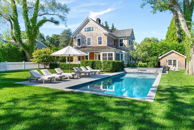 back of property with a fenced in pool, an outdoor structure, a lawn, and a patio area