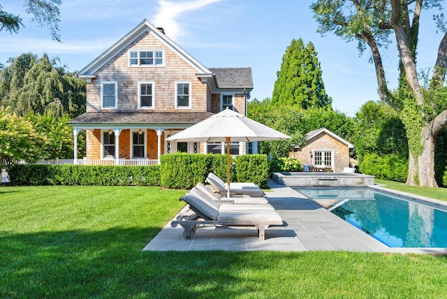 rear view of property with a fenced in pool, an outbuilding, a lawn, and a patio area