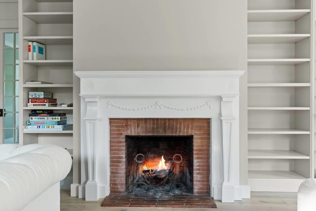 details featuring a brick fireplace, hardwood / wood-style floors, and built in shelves