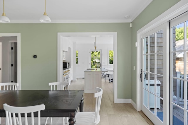 dining space with crown molding and light hardwood / wood-style flooring