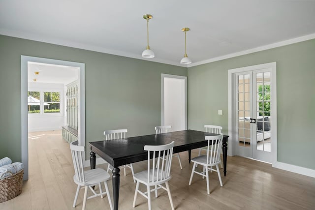 dining area with ornamental molding, light wood-type flooring, and french doors