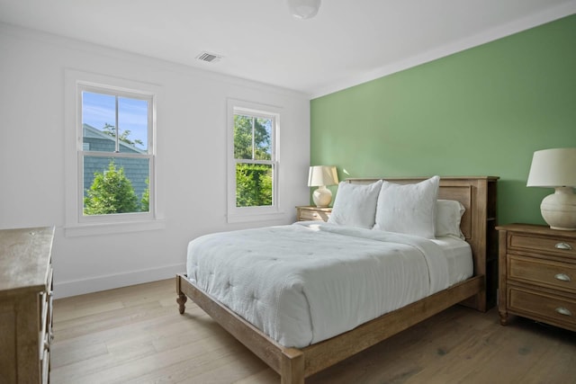 bedroom featuring crown molding and light hardwood / wood-style flooring