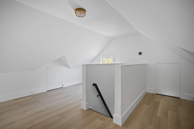 additional living space featuring vaulted ceiling and light wood-type flooring