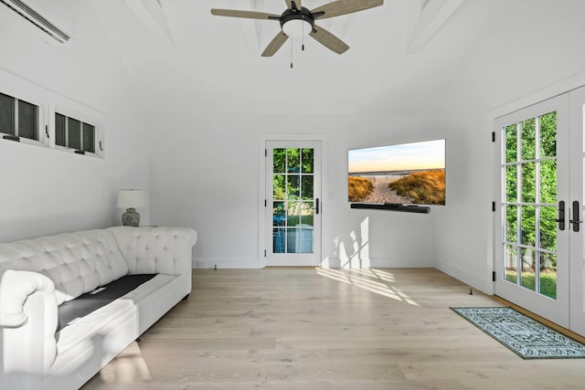 living room featuring plenty of natural light, light hardwood / wood-style flooring, beam ceiling, and french doors