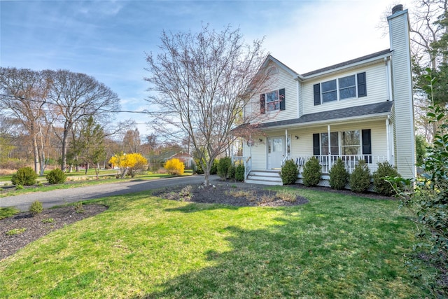 traditional-style home featuring a chimney, a porch, and a front yard