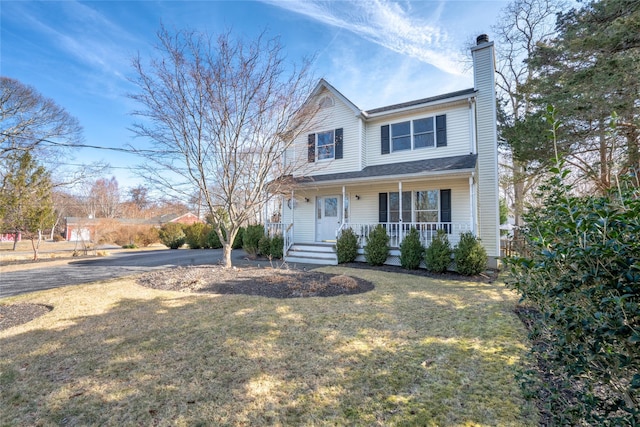 traditional-style house with a front yard, a chimney, covered porch, and aphalt driveway