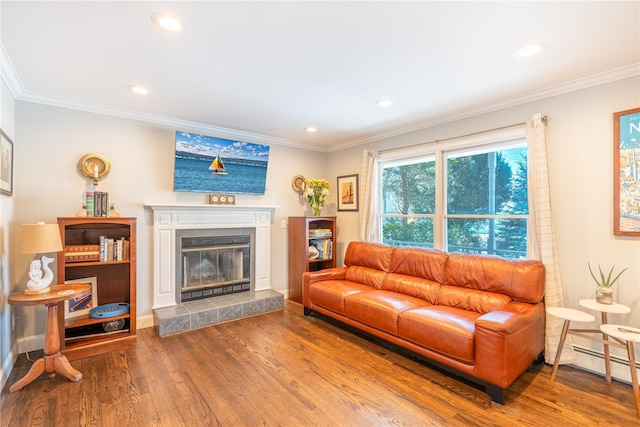 living area with a baseboard heating unit, recessed lighting, wood finished floors, a fireplace, and ornamental molding