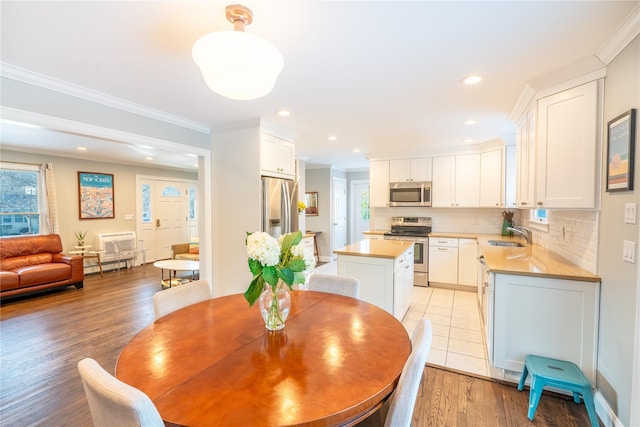 dining area with a baseboard radiator, light wood finished floors, crown molding, and recessed lighting
