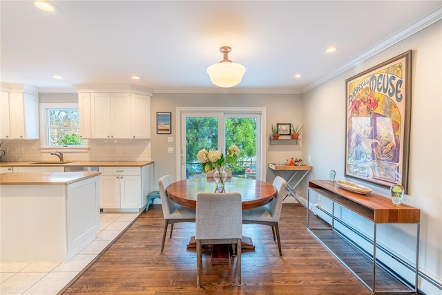 dining area with baseboard heating, crown molding, light wood-style floors, and recessed lighting