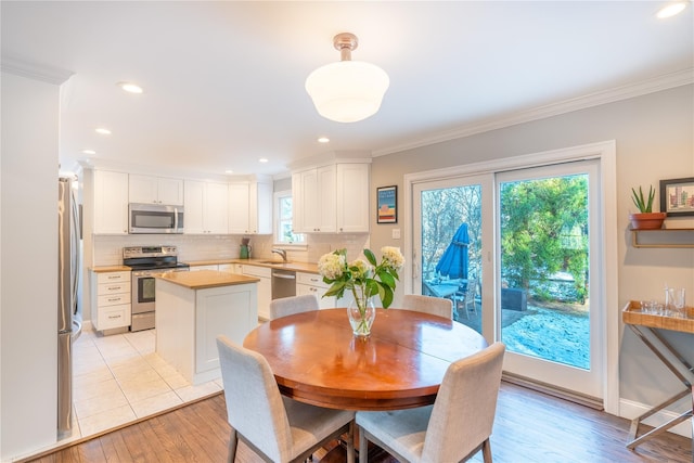 dining area with light wood-type flooring, recessed lighting, and ornamental molding