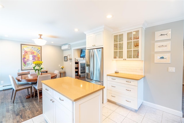 kitchen with a center island, stainless steel fridge, a wall mounted air conditioner, glass insert cabinets, and crown molding