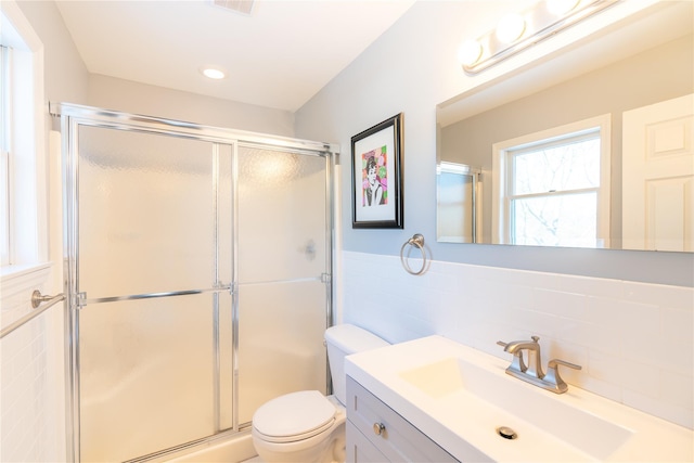 full bath with a shower stall, toilet, vanity, and tile walls