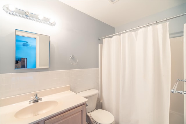 bathroom featuring a shower with curtain, toilet, tile walls, wainscoting, and vanity