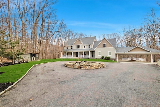 view of front of house with a porch, aphalt driveway, a detached carport, and a front lawn