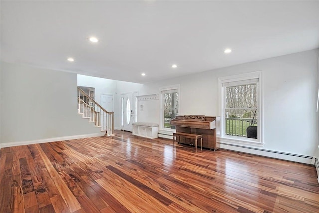 unfurnished living room with a baseboard heating unit, stairs, hardwood / wood-style flooring, and recessed lighting