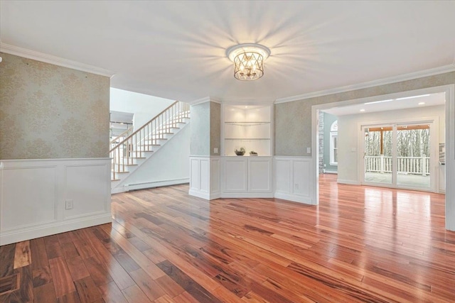 interior space featuring a chandelier, stairway, wainscoting, wallpapered walls, and hardwood / wood-style floors