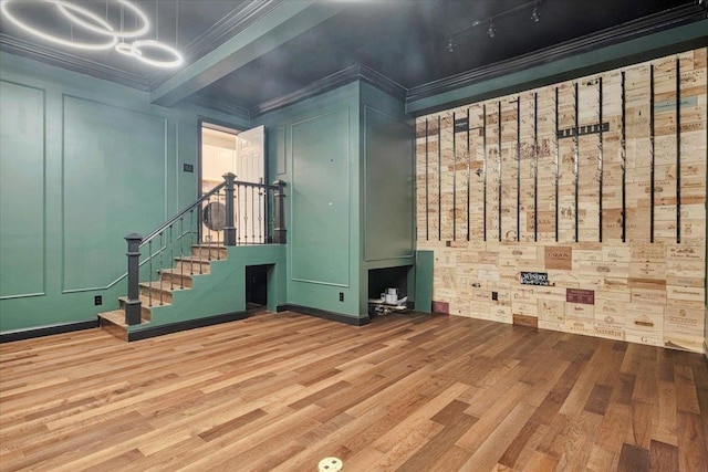 interior space with a decorative wall, ornamental molding, a chandelier, wood finished floors, and stairs