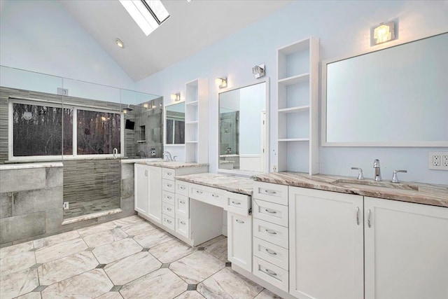 bathroom with a tile shower, vanity, and lofted ceiling with skylight