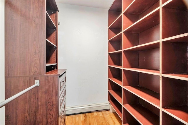 walk in closet with light wood-style flooring and baseboard heating