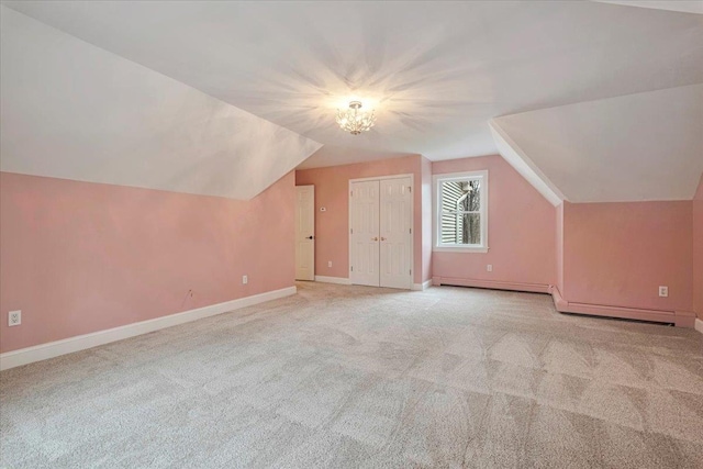 bonus room featuring baseboards, a chandelier, vaulted ceiling, and light carpet