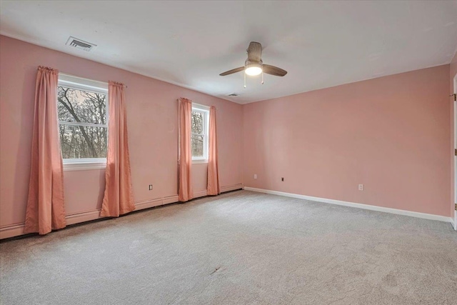 carpeted spare room featuring visible vents, ceiling fan, plenty of natural light, and baseboards