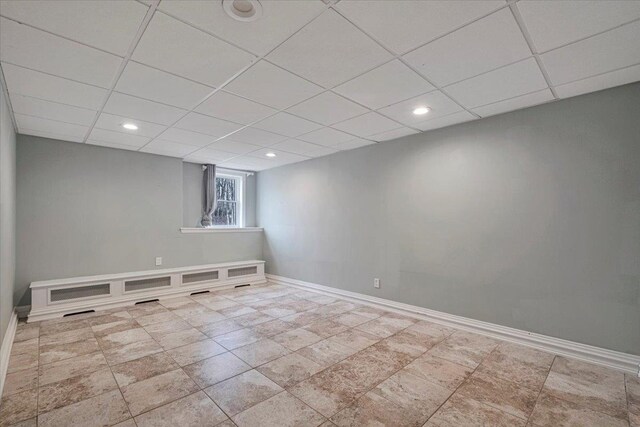 below grade area featuring baseboards, recessed lighting, and a drop ceiling