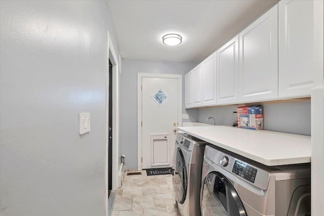 laundry room with cabinet space, washer and dryer, and stone finish flooring
