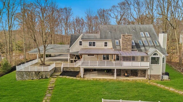 rear view of property featuring a carport, a patio, a chimney, a yard, and a deck
