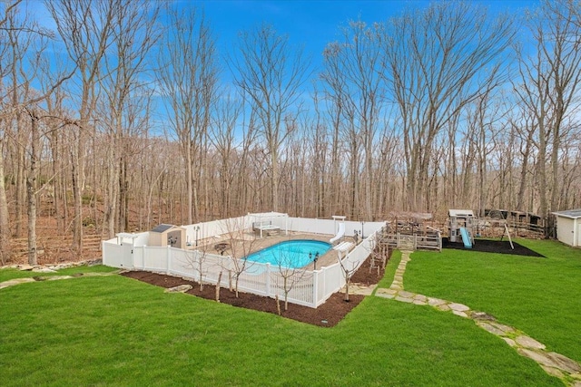 view of pool featuring a yard, a wooded view, a fenced backyard, an outdoor structure, and a fenced in pool
