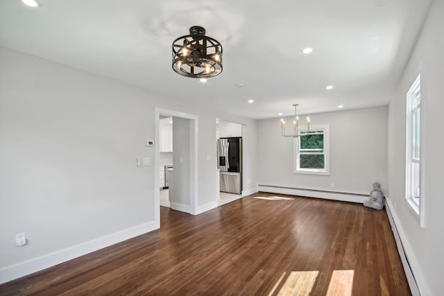 unfurnished living room with an inviting chandelier, dark wood-type flooring, and a baseboard heating unit