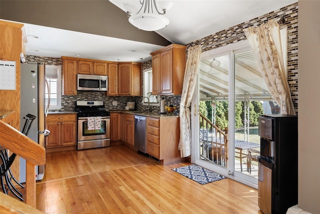 kitchen featuring lofted ceiling, sink, stainless steel appliances, tasteful backsplash, and light hardwood / wood-style floors