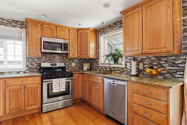 kitchen featuring appliances with stainless steel finishes, light stone countertops, sink, and decorative backsplash