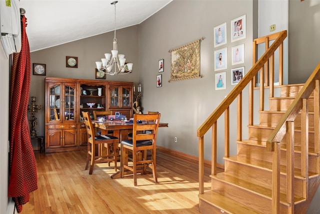 dining space featuring an inviting chandelier, vaulted ceiling, and light wood-type flooring