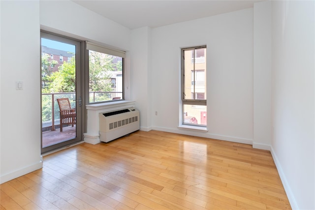 spare room featuring radiator and light hardwood / wood-style flooring