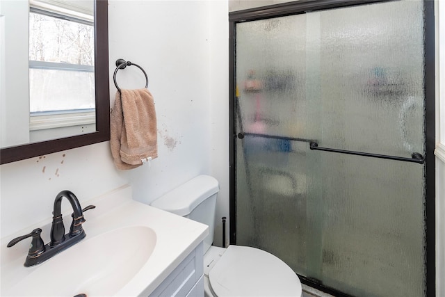 bathroom featuring vanity, toilet, and a shower with shower door