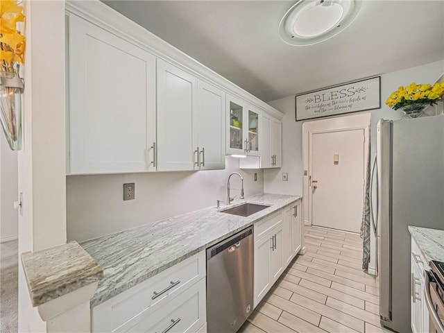 kitchen featuring white cabinetry, appliances with stainless steel finishes, light stone countertops, and sink