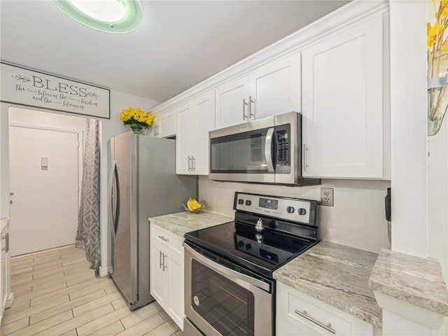 kitchen with white cabinetry, appliances with stainless steel finishes, and light stone countertops