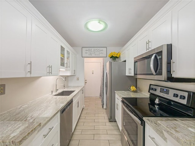 kitchen featuring light stone counters, stainless steel appliances, sink, and white cabinets