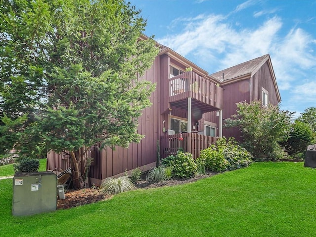 view of home's exterior with a balcony and a yard