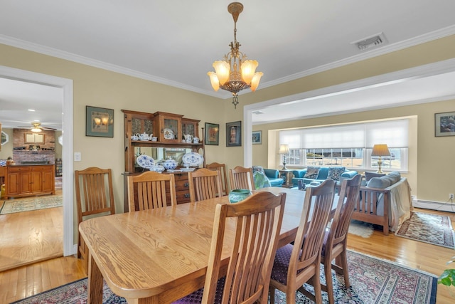 dining area featuring crown molding, ceiling fan with notable chandelier, and light hardwood / wood-style flooring