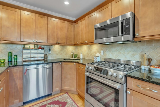 kitchen featuring sink, appliances with stainless steel finishes, decorative backsplash, dark stone counters, and light wood-type flooring