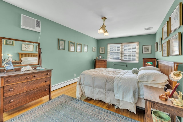 bedroom with a wall mounted air conditioner, a chandelier, light wood-type flooring, and a baseboard heating unit