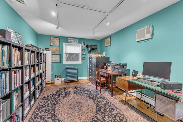 office space featuring hardwood / wood-style flooring, an AC wall unit, and track lighting