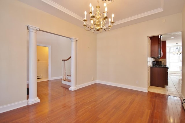 unfurnished dining area featuring decorative columns, stairway, wood finished floors, an inviting chandelier, and a tray ceiling