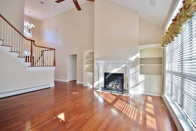 unfurnished living room featuring visible vents, a baseboard radiator, a fireplace with flush hearth, stairway, and wood finished floors