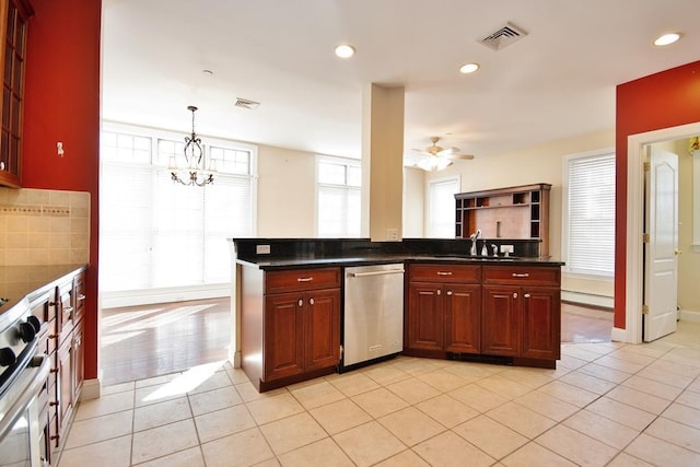 kitchen with reddish brown cabinets, visible vents, dark countertops, pendant lighting, and stainless steel dishwasher